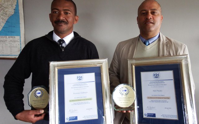 Vlnr is Tommy Volkwyn (hoof) en Neil Pedro (adjunkhoof) van Gansbaai Primêr met hul trofeë en geraamde sertifikate 